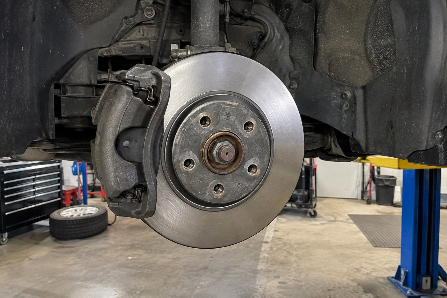 Front brake rotor and caliper photographed on the lift during inspection