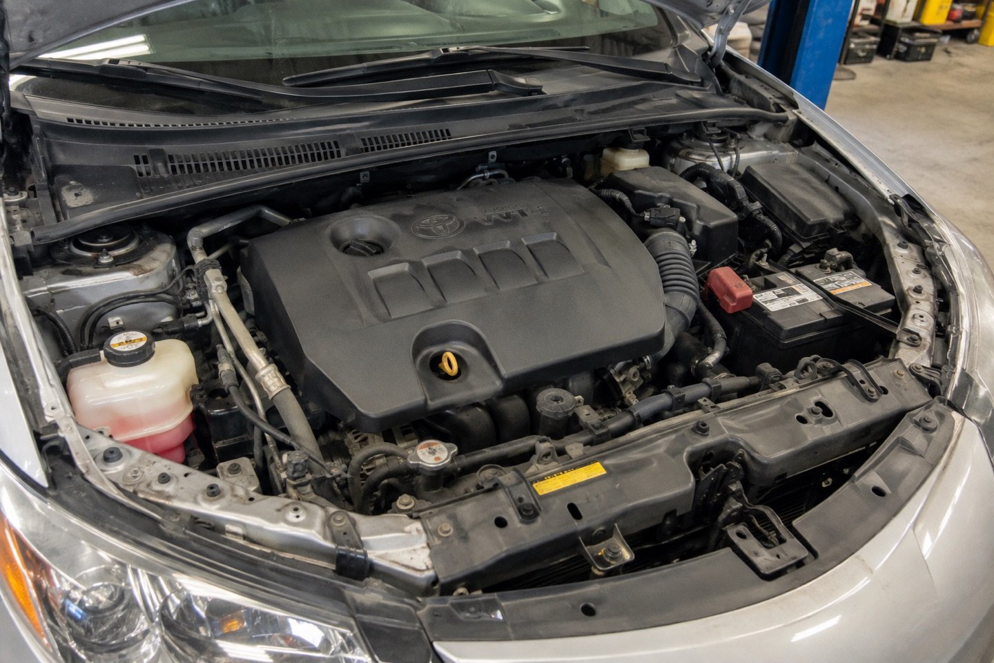 Open engine bay of a silver sedan in the workshop