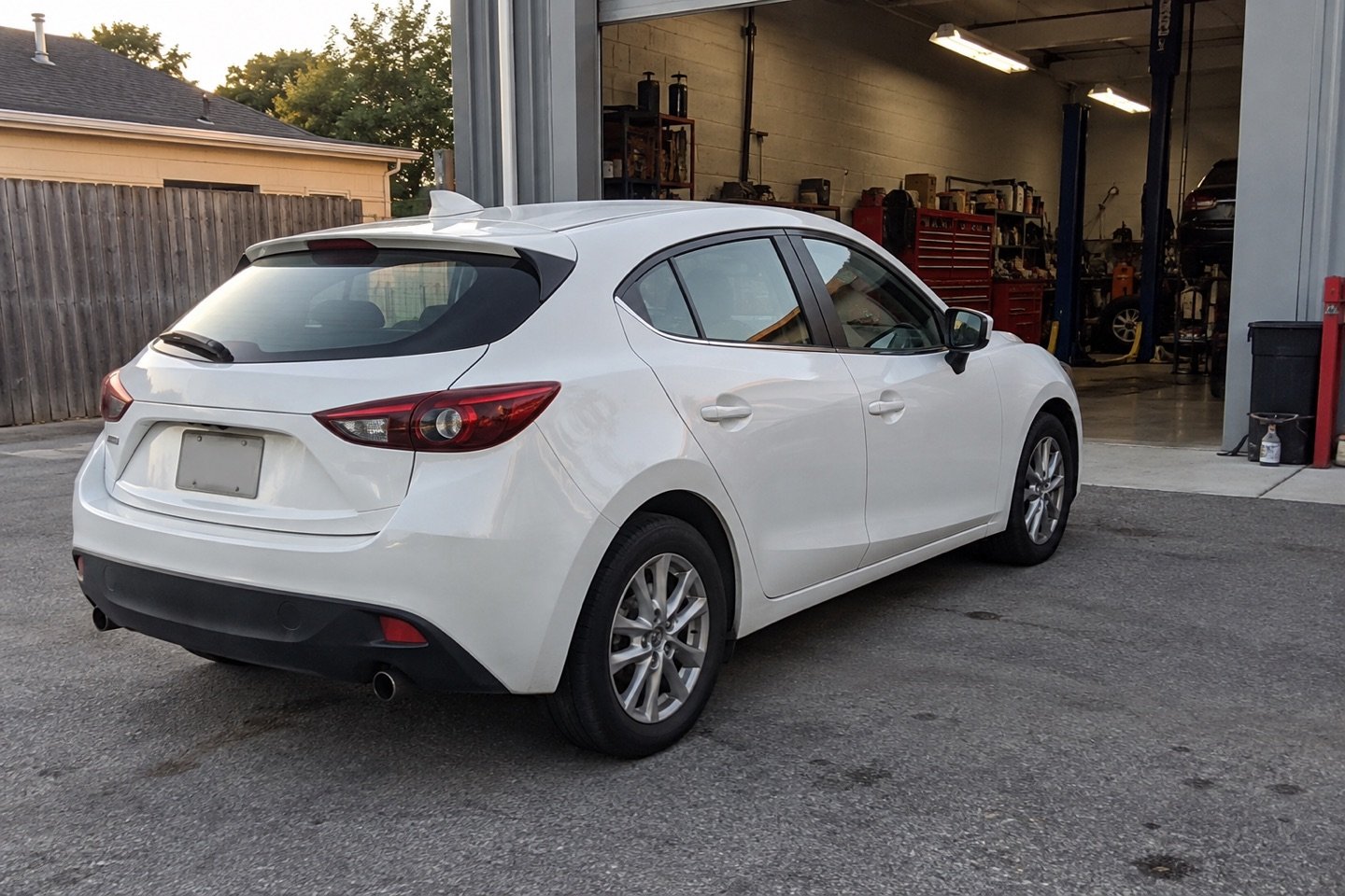 White hatchback parked outside an open service bay