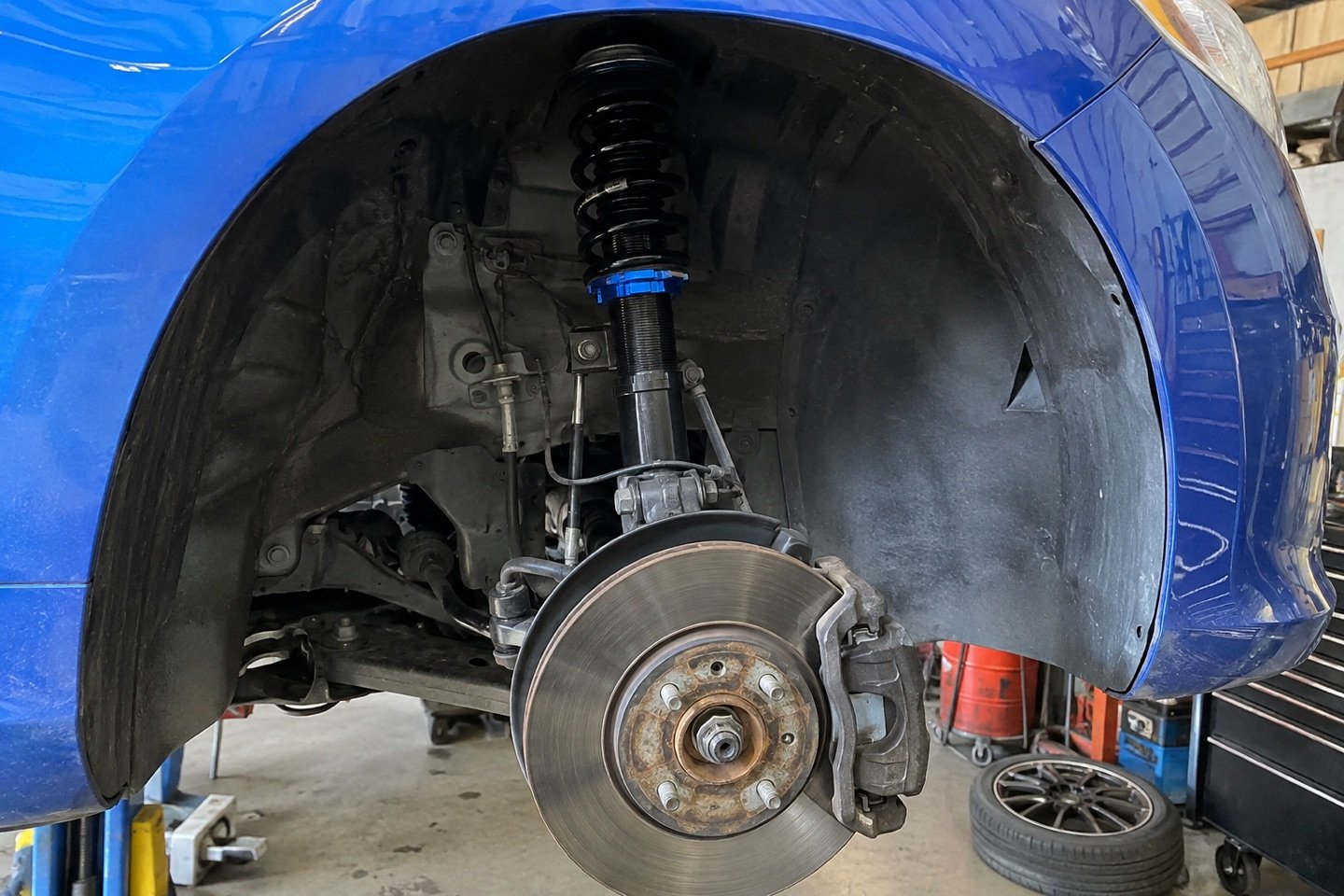 Installed coilover suspension inside a blue hatchback wheel well